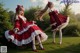 A woman in a red and white dress sitting on a tree stump.