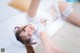 A woman laying on top of a bed in a white dress.