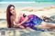 A woman in a colorful dress laying on the beach.