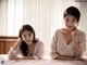 A couple of women laying on top of a bed.