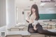 A woman sitting on top of a desk in a classroom.