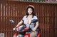 A woman sitting on a red motorcycle wearing a helmet.