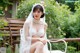 A woman in a wedding dress sitting on a bench.