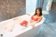 A woman in a red bikini sitting in a bathtub.